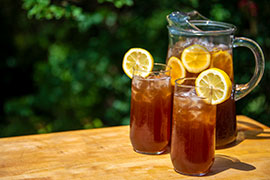 pitcher and glasses of iced tea with lemon on wood table